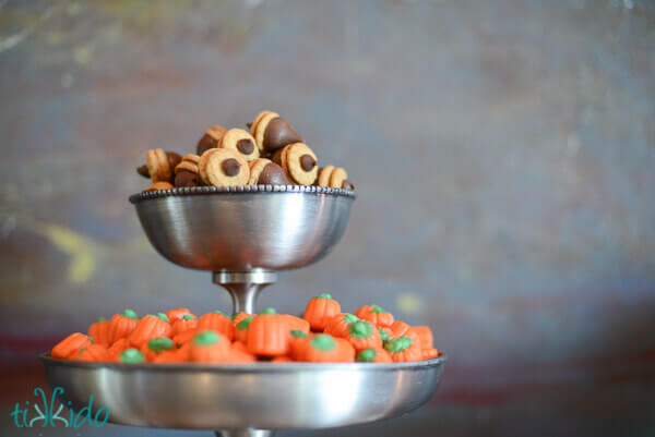 Chocolate acorns in a tiered serving tray with candy corn pumpkin candies.