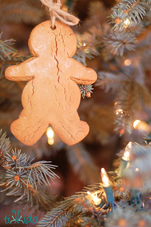 Gingerbread man cookie turned into a Christmas ornament hanging on a Christmas tree.