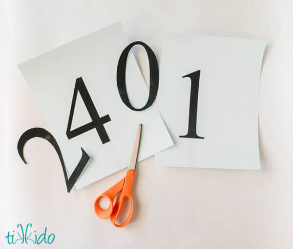Numbers being cut out of cardstock to embellish a balloon tassel.