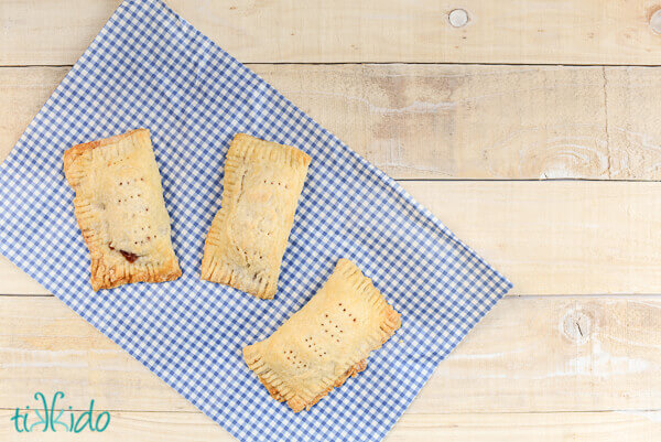 Homemade cherry hand pies on a blue gingham napkin.