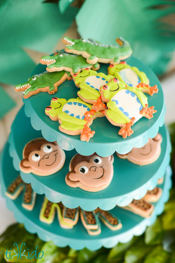 Crocodile, tree frog, and monkey sugar cookies on a tiered serving tray.