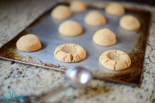 Peanut butter cookies being shaped into thumbprint cookies to be filled with nutella.