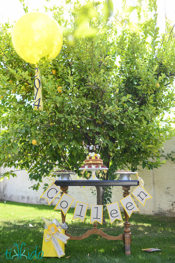 Yellow balloon with a graduation balloon tassel decoration decorating a graduation party dessert table.