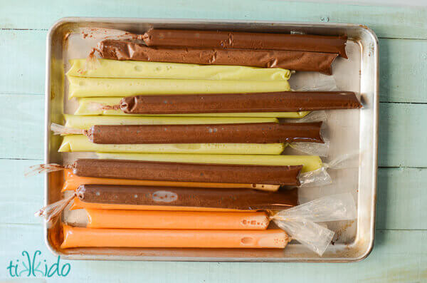 Sheet pan full of dairy free popsicles and fudgesicles, on a light blue wooden surface.