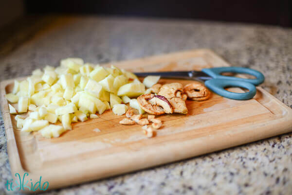 Dried apple and fresh apple chunks on a wooden cutting board.