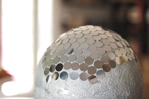 Silver piñata being covered with silver paillettes.