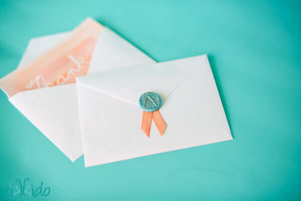 Faux wax seal and ribbon on the envelope of a thank you note.