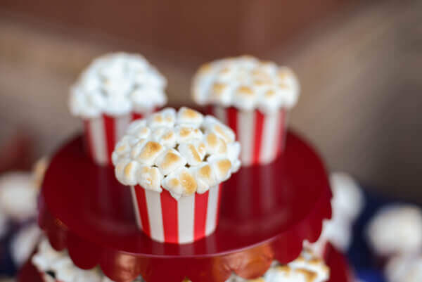 Three popcorn cupcakes sitting on a red cake plate.