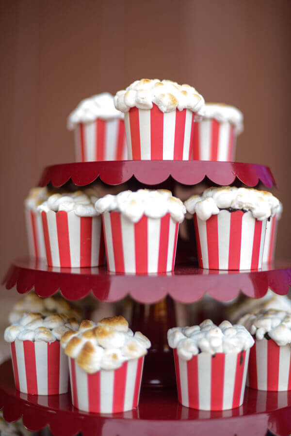 Three tiered red cake stand covered in popcorn cupcakes.