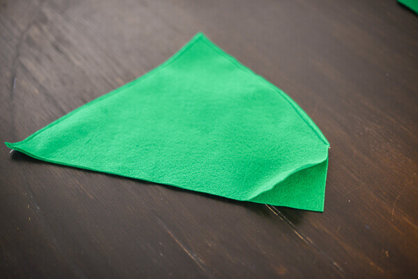 Two pieces of green felt cut out to make a Peter Pan hat and sewn along two of the four edges.