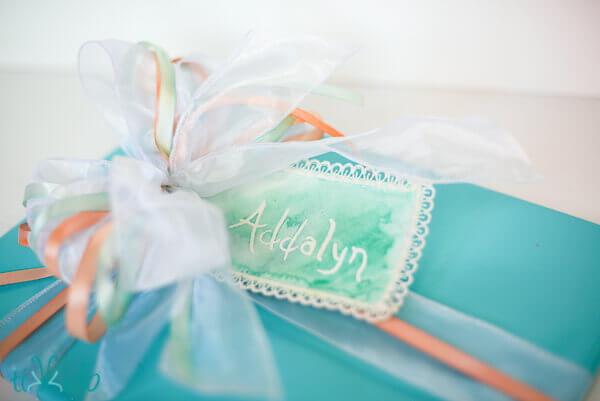 Gift wrapped in turquoise paper and finished with a bow made from painted ribbon.