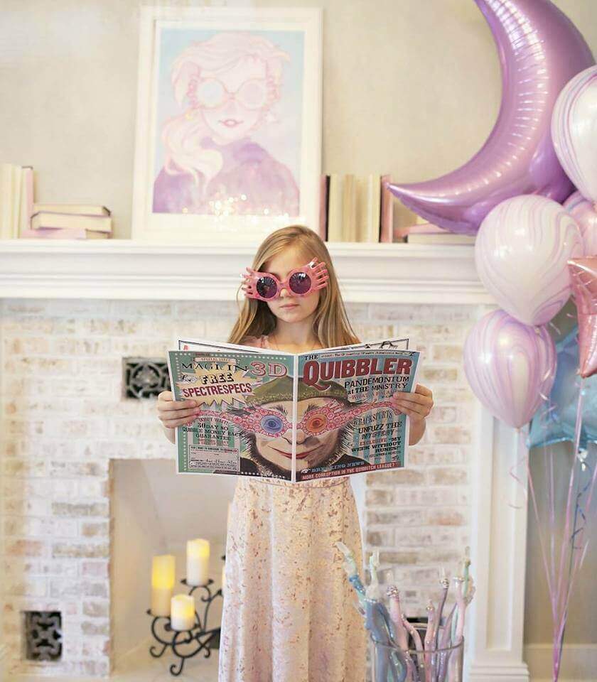 Little girl dressed as Luna Lovegood holding a copy of the Quibbler newspaper.