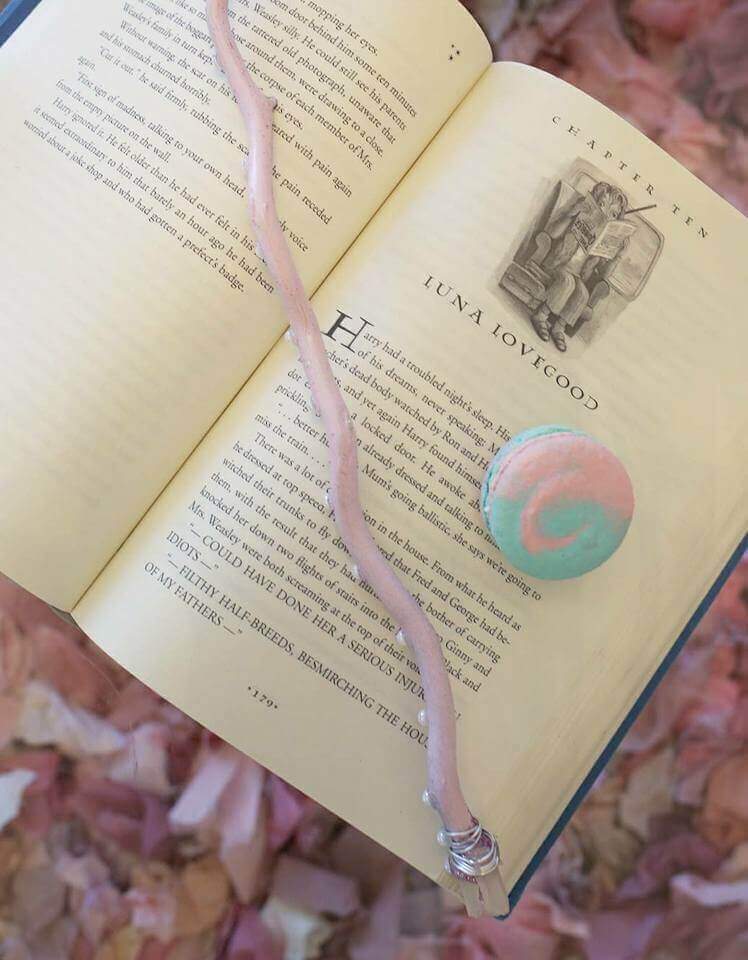 Lavender luna lovegood magic wand with crystal topper and a pink and blue swirled macaron on an open Harry Potter book.