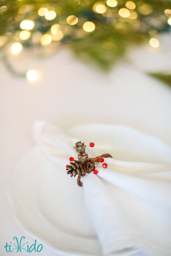Pinecone napkin ring made with real pine cones and Swarovski crystals on a white napkin.