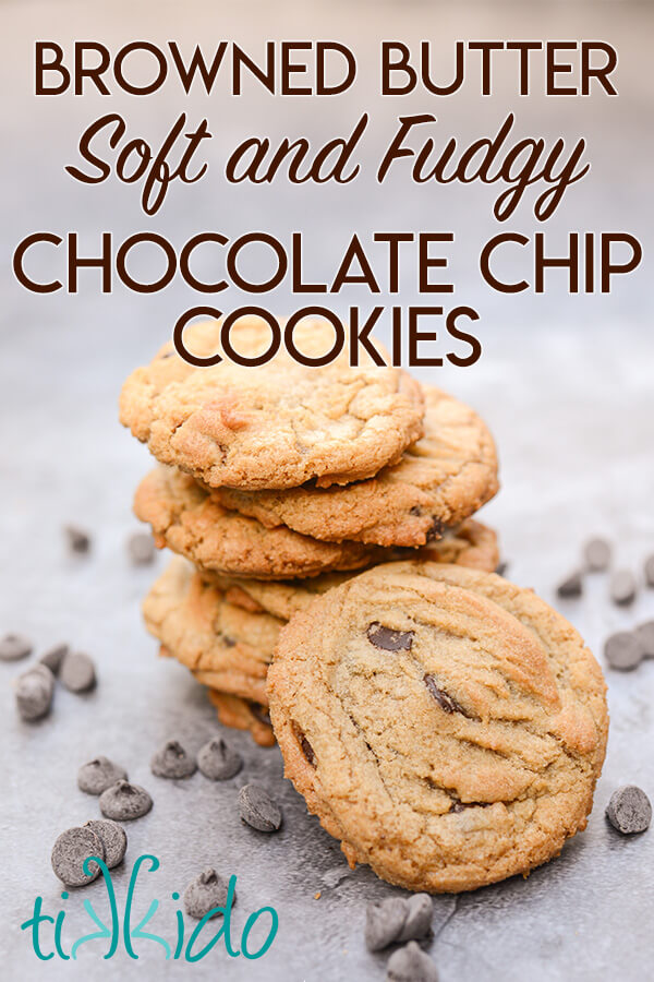 Stack of browned butter chocolate chip cookies on a grey surface surrounded by chocolate chips.  Text overlay reads "browned butter soft and fudgy chocolate chip cookies."