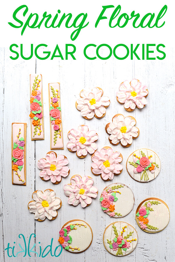 sugar cookies decorated with royal icing flowers in bright spring colors on a white wooden surface.  Text overlay reads "Spring Floral Sugar Cookies."