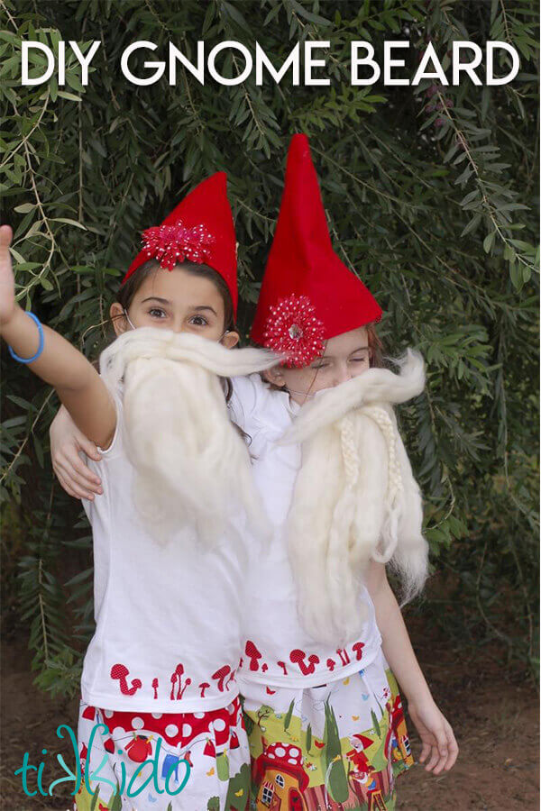 Two little girls hugging, wearing gnome hats and gnome beards.
