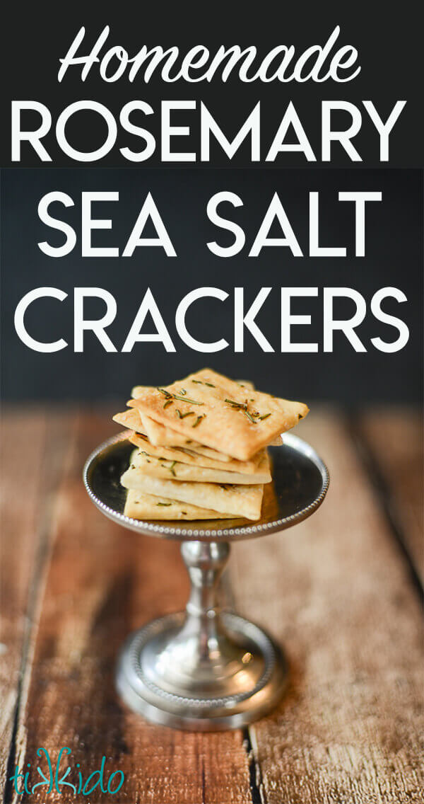 Homemade crackers topped with rosemary and salt stacked on a small silver stand.