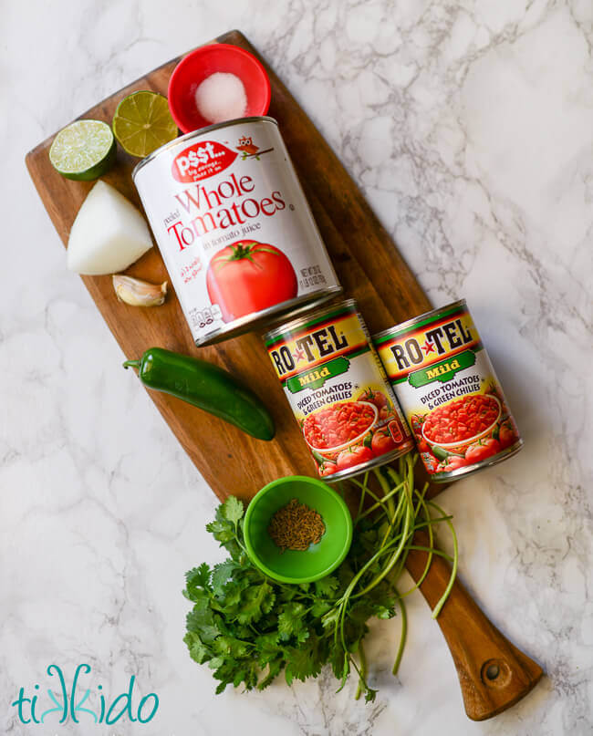 Ingredients for red salsa on a wooden cutting board.