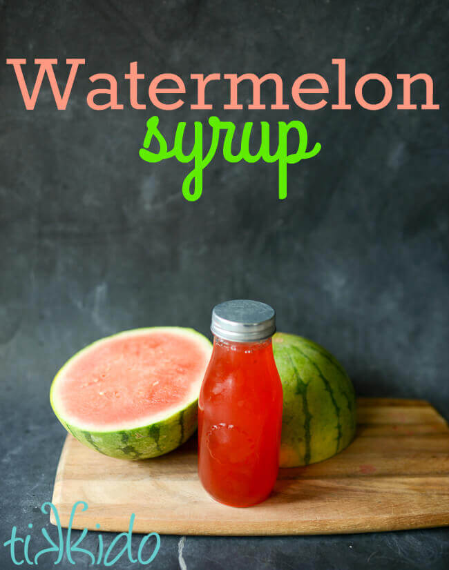 Homemade Watermelon Syrup in a bottle in front of a whole watermelon sliced in half on a wooden cutting board, with text overlay reading "Watermelon Syrup."