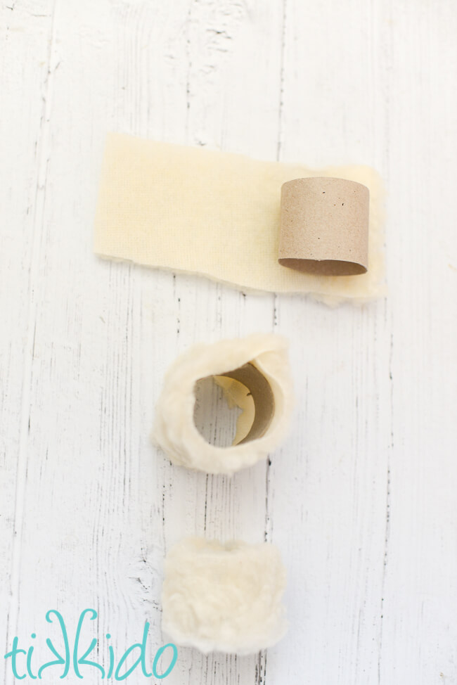 Cardboard tube being covered in faux shearling fabric to make Easter Sheep Napkin Rings.