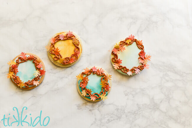 Four fall leaf wreath decorated sugar cookies on a white marble background.
