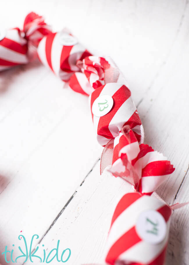 DIY Advent Calendar garland made with red and white fabric on a white wooden background.