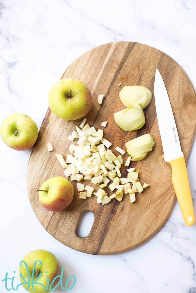 Apples being chopped on a wooden chopping board for apple muffin recipe