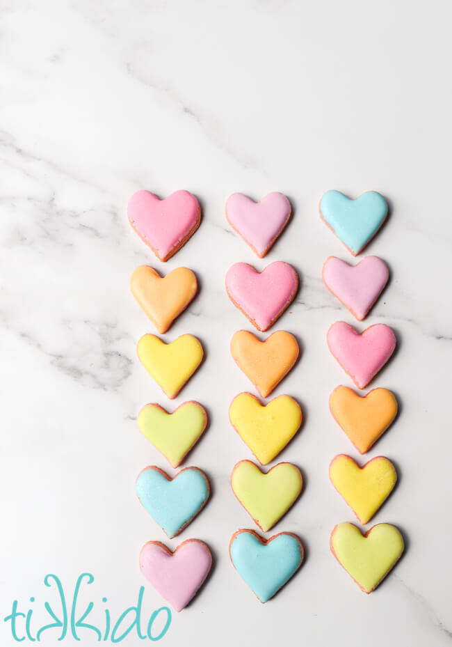 Mini sugar cookies that look like conversation hearts Valentine's day candies on a marble surface.