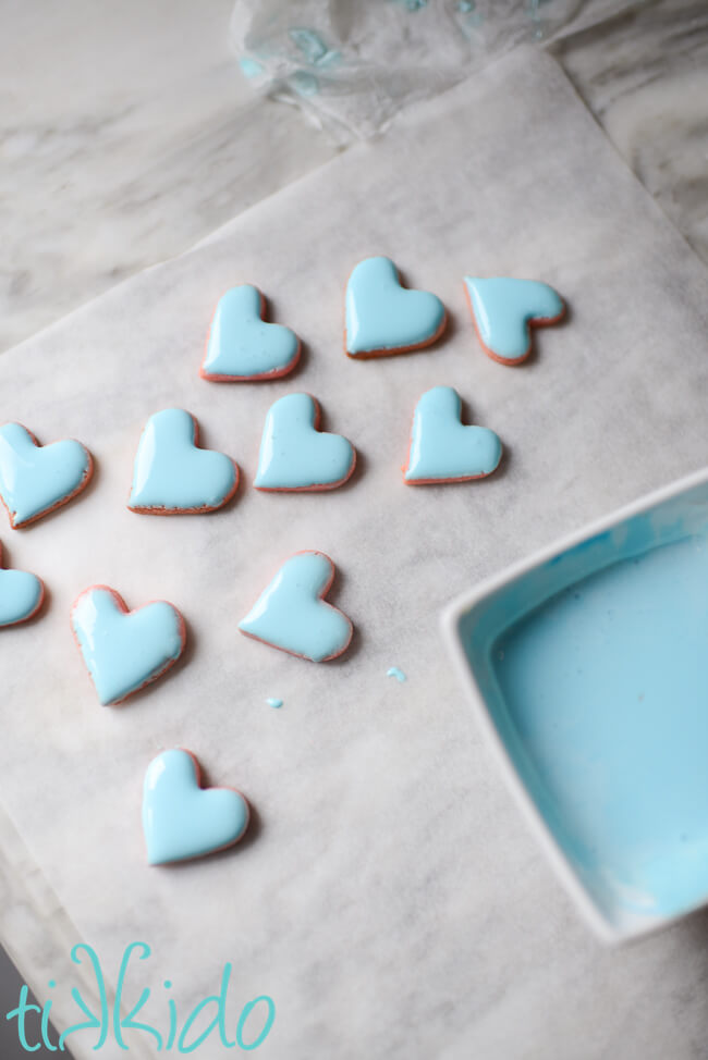 Mini heart cookies coated in light blue royal icing to make Conversation Heart Sugar Cookies