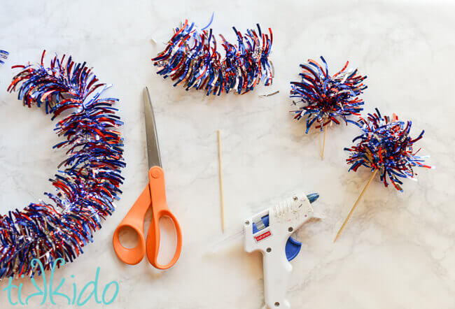 patriotic tinsel garland being cut and glued into fireworks cupcake toppers