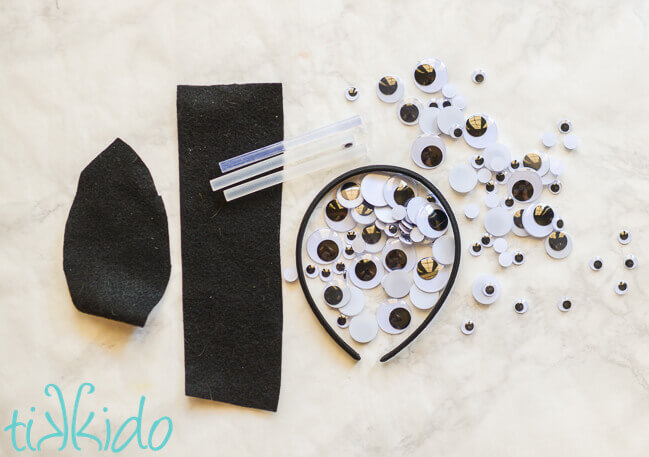 Materials for making a Googly eyes Halloween headband on a white marble surface.