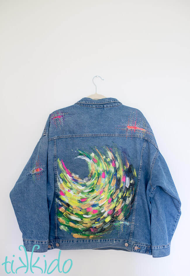 Brightly painted denim jacket on a white background.
