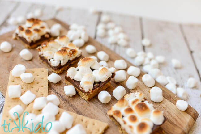 No bake s'mores bar squares on a wooden cutting board.