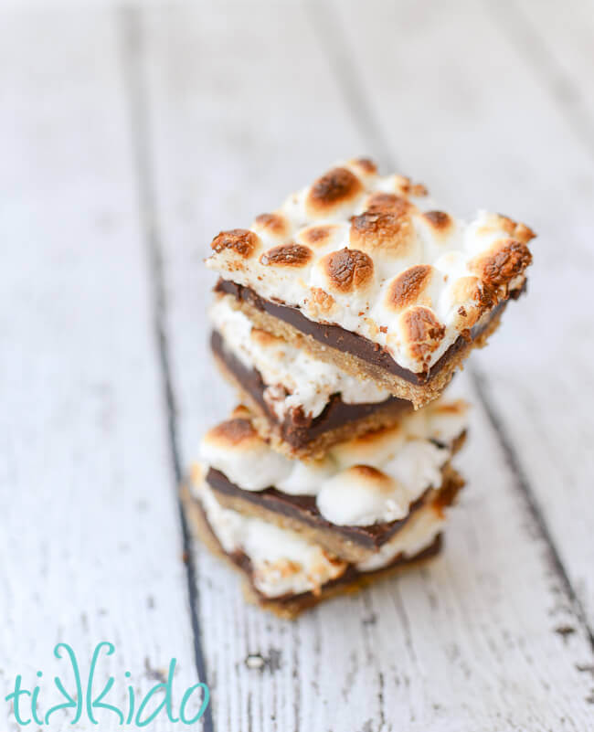 Stack of no bake smores bars on a weathered white wooden surface.