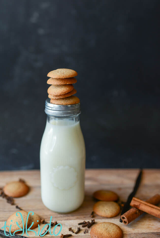Pumpkin Spice Vanilla Wafer Cookies stacked on a bottle of milk, surrounded by cookies and whole spices.