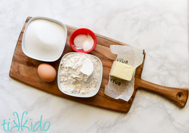 Cobbler topping ingredients measured and set out on a wooden cutting board on a white marble surface.