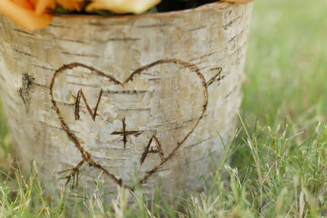 Birch bark covered zinc floral container with the letters N + A in a heart carved into the bark.