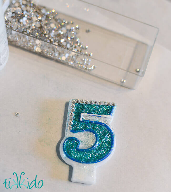 Rhinestones being glued to the outline of the customized number candle.
