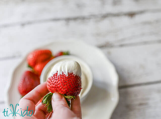 Hand holding a strawberry dipped in easy fruit dip.