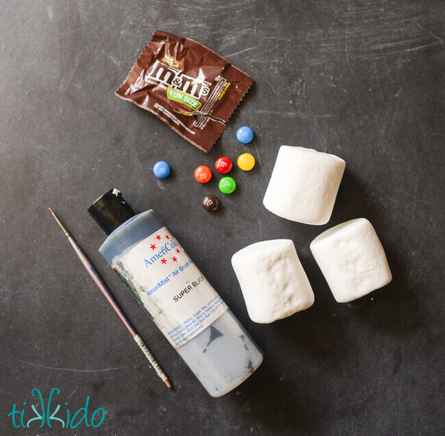 Materials for making Ghostbusters Stay Puft Marshmallow Treats on a black chalkboard surface.