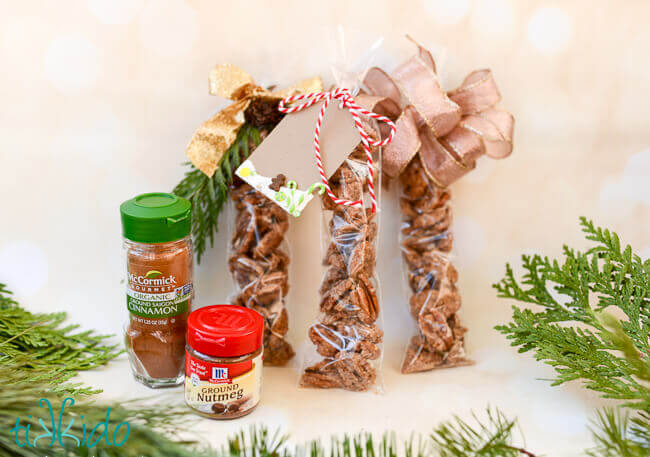 Gingerbread Spiced Candied Pecans packaged in long, narrow plastic bags, topped with ribbons and gift tags.