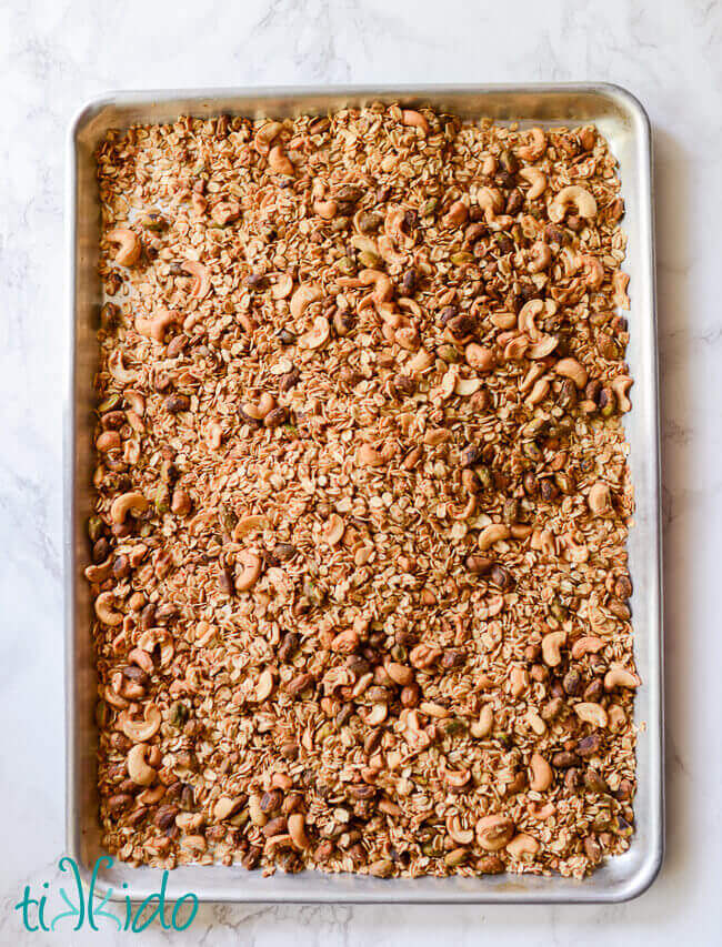 Sheet pan filled with homemade granola on a white marble surface.