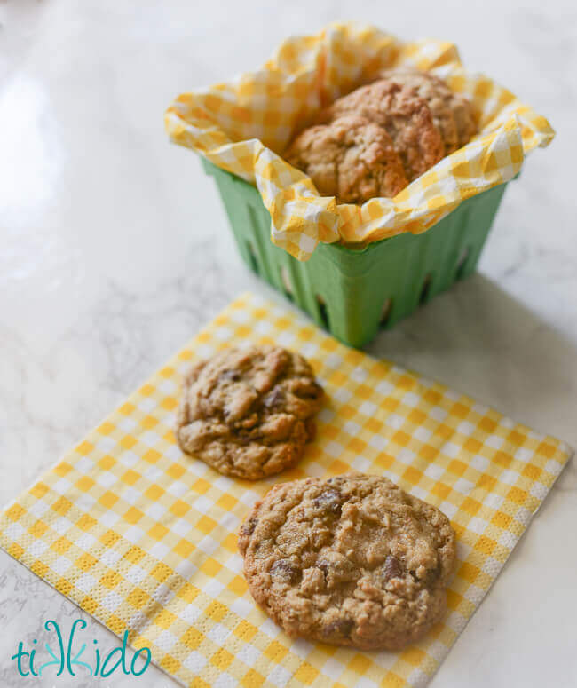 oatmeal chocolate chip cookies in a small basket and on a yellow gingham napkin.