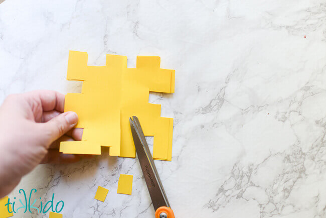 Yellow paper being cut into life sized pixelated Minecraft flowers for a Minecraft birthday party.