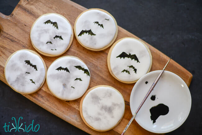 Painting bat silhouettes on the full moon decorated sugar cookies.