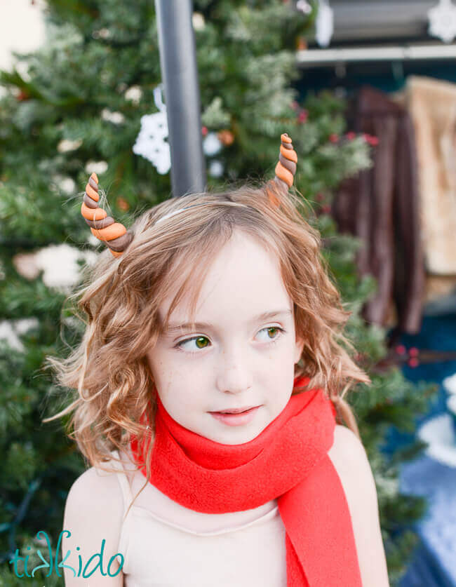 Little girl with horns and a red scarf wearing a Mr. Tumnus Faun Costume.