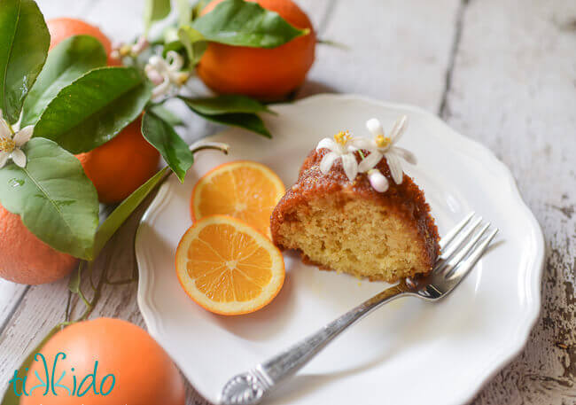 Slice of orange bundt cake topped with fresh orange blossoms.