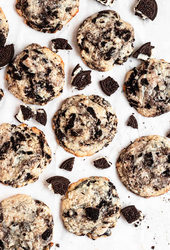 Oreo cheesecake cookies on parchment paper, surrounded by crushed Oreos.