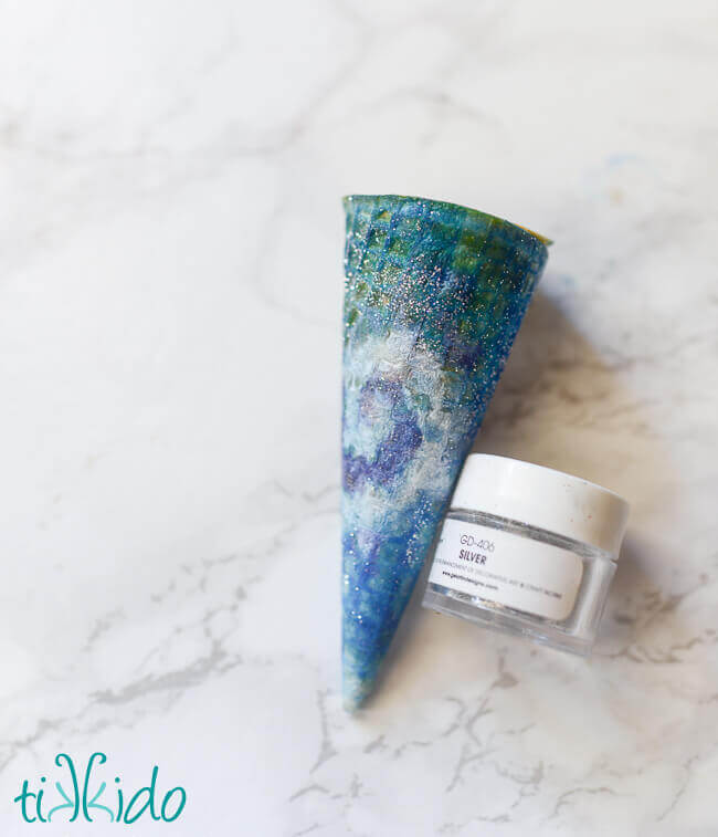 Ice cream cone painted with food coloring like a swirling galaxy with silver disco dust stars.